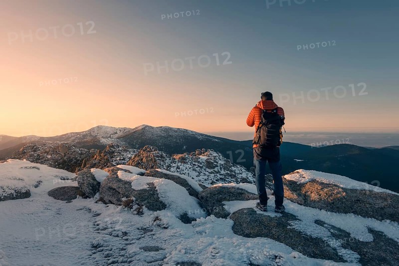 A photographer captures the breathtaking snowy landscape of Siete Picos in Guadarrama Mountains, Madrid, as the sun casts a golden glow over the peaks