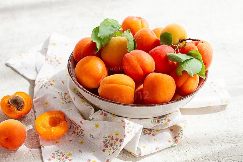 Fresh apricots in a bowl, on a bright table, natural light, top view, no people