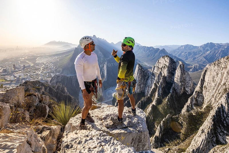 Adventurer receiving mountaineering and rappelling lessons at the breathtaking Eagleâ€™s Nest in Monterrey, Mexico, surrounded by stunning mountain landscapes and clear blue skies