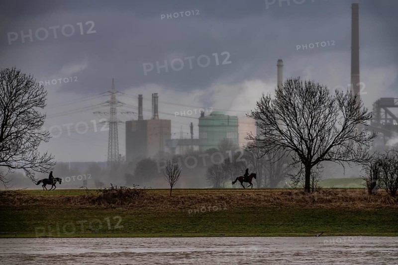 Riders on the banks of the Rhine opposite Krefeld-Uerdingen, in winter, the Krupp-Mannesmann metallurgical plant, HKM in Duisburg-Hüttenheim, coking plant, gas power plant, cooling towers, Rheinauen in Duisburg-Mündelheim, North Rhine-Westphalia, Germany