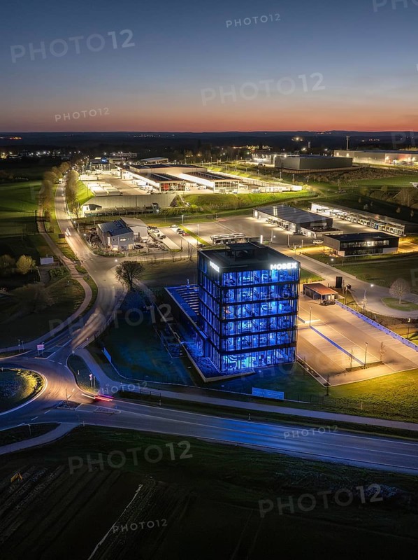 A modern illuminated building surrounded by streets and other structures at night, Nagold, Black Forest, Germany