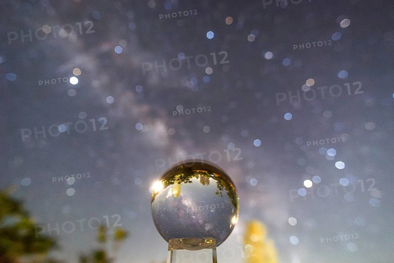 An enchanting image capturing the Milky Way galaxy mirrored in a crystal ball, set against a blurry night sky at Sequoia National Park