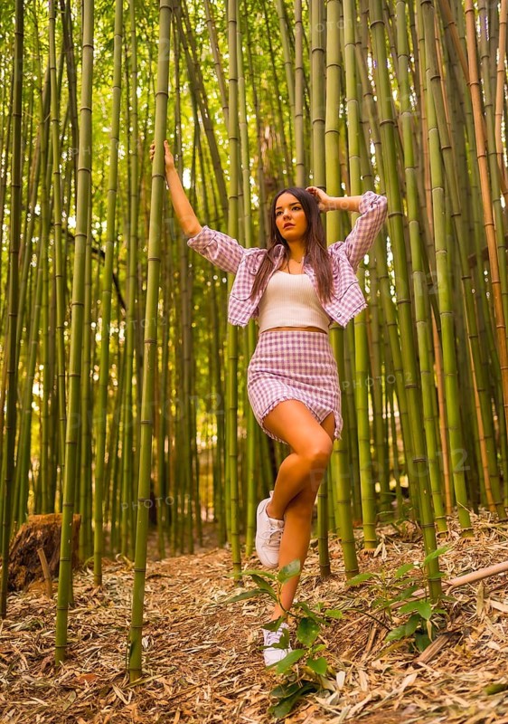 Young caucasian girl with a pink skirt in a bamboo forest. Enjoying summer holidays in a tropical climate, lifestyle of a girl walking and smiling in the forest