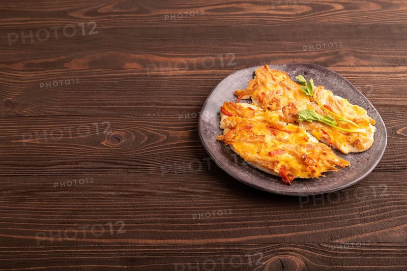 Baked chicken meat with cheese and tomatoes on brown wooden background. side view, copy space