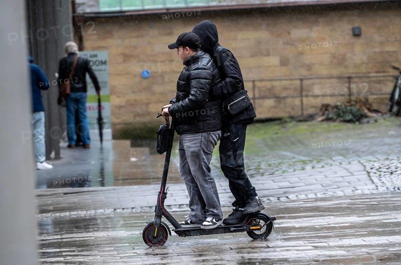 City center, shopping street, Kettwiger Straße pedestrian zone in Essen, 2 young men on an e-scooter, electric scooter, rainy weather, North Rhine-Westphalia, Germany