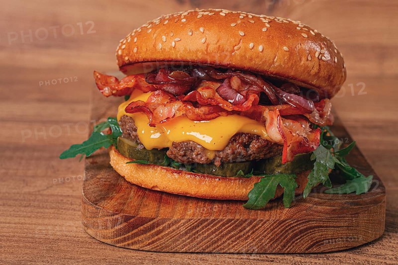 Burger with beef and bacon, with arugula and caramelized onions, pickles, sauce, homemade, no people
