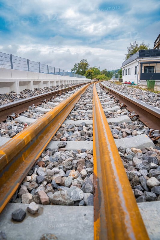 Close-up view of rails with stone bedding running into the distance under a cloudy sky, track construction, rail delivery for Hermann Hessebahn, Calw, Black Forest, Germany