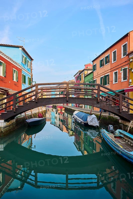 Colorful houses and a bridge 'Love viewing bridge' going over the waterway with boats lying in the water on the island of Burano, Italy