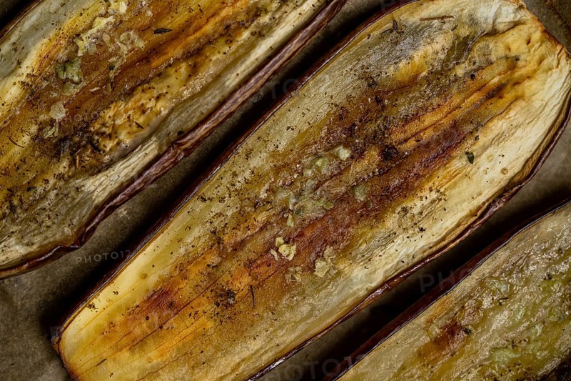 Close-up of baked eggplant slices seasoned with spices, showing a rustic texture. Perfect for lovers of Mediterranean cuisine, healthy eating and plant-based dishes