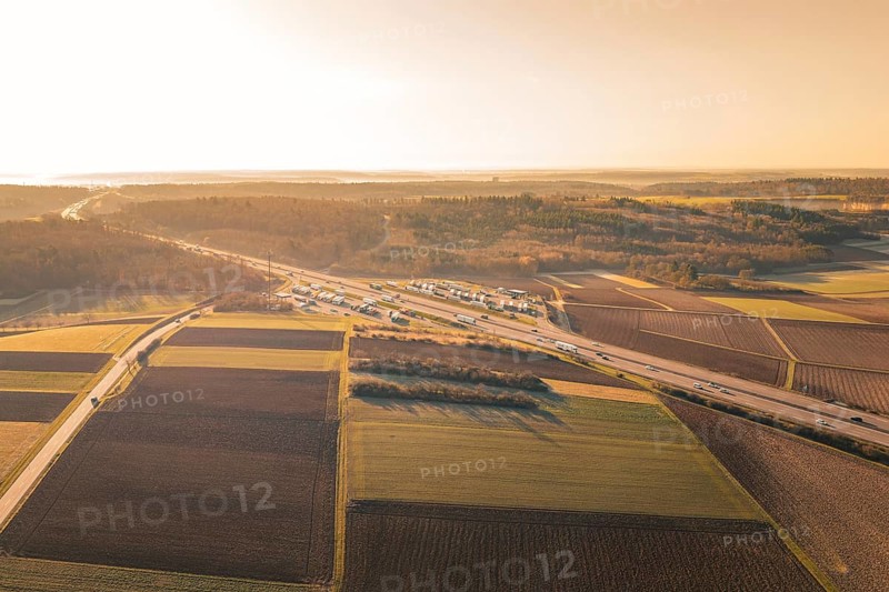 Aerial view of a vast landscape with a busy highway, fields and a warm sunset, A8 near Wurmberg, Pforzheim, Germany