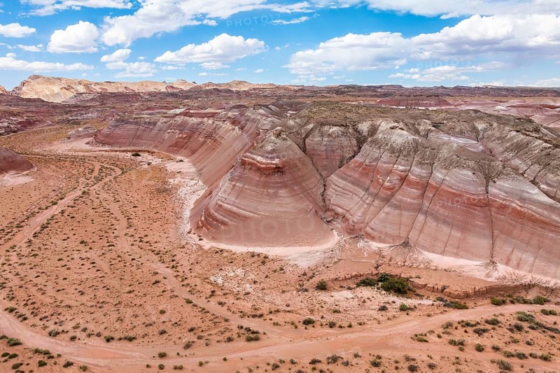 Drone shot capturing the expansive and multi-hued terrain of Hanksville, Utah, featuring striking rock formations and sparse vegetation
