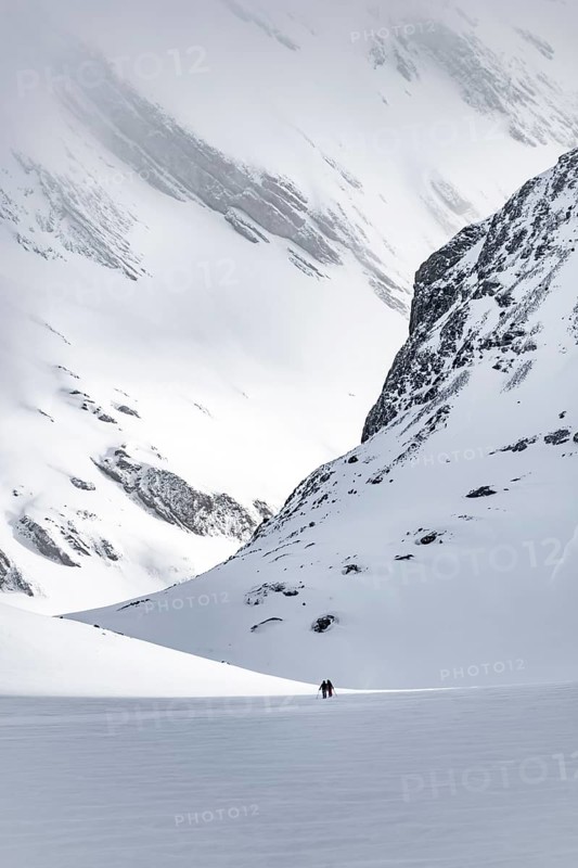 Dramatic atmosphere, Ski tourers in the vast landscape, Snow-covered mountain landscape, Bernese Alps, Bernese Oberland, Switzerland