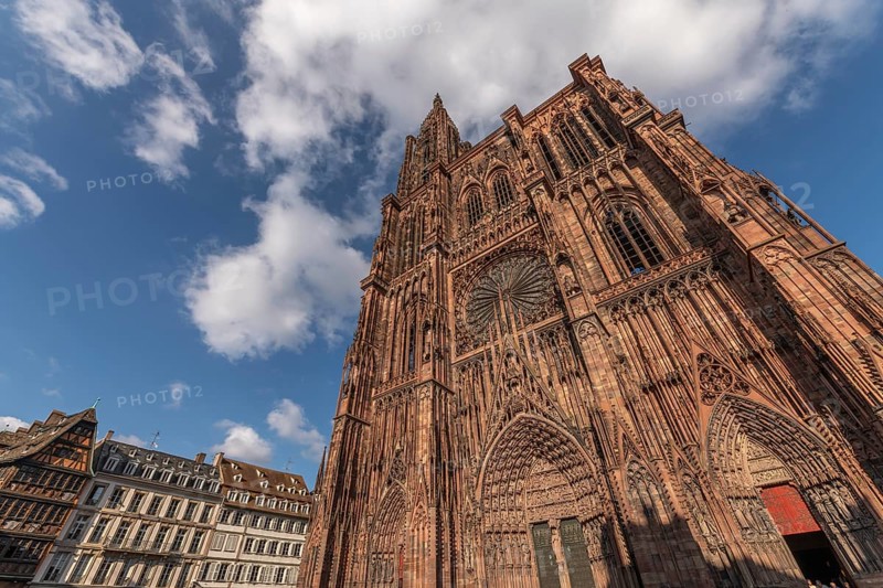 Strasbourg's Notre Dame Cathedral stands majestically there. Its magnificent architectural details are clearly visible under the blue, cloudy sky. Bas Rhin, Alsace, France
