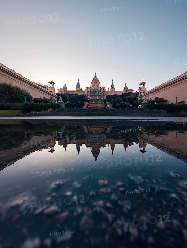 A serene and symmetrical reflection of the majestic National Art Museum of Catalonia in Barcelona captured during the tranquil hours of dusk