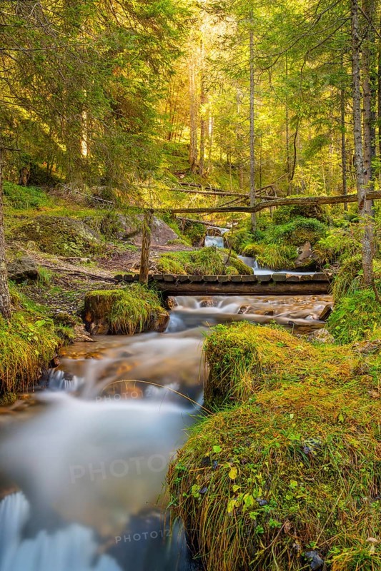 View of a wooden bridge leading over a torrent, long exposure, Dolomites, Puez-Geisler nature park Park, St. Magdalena, Funes, Villnößtal, South Tyrol, Italy