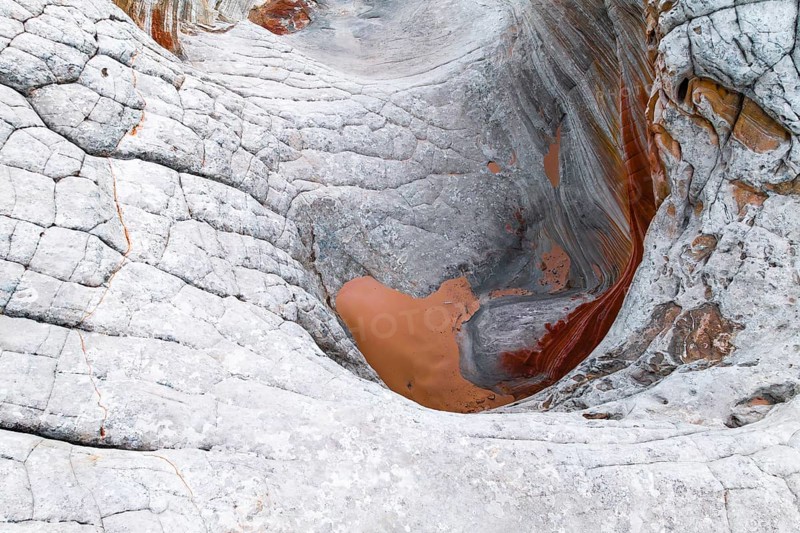 Stunning close-up view of abstract, white rocks with orange and red undertones showcasing intricate, swirling patterns and textures on a rugged terrain