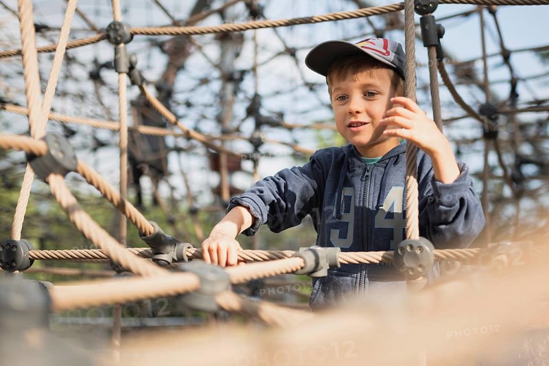 A 5-year-old boy climbs on the ropes at the playground