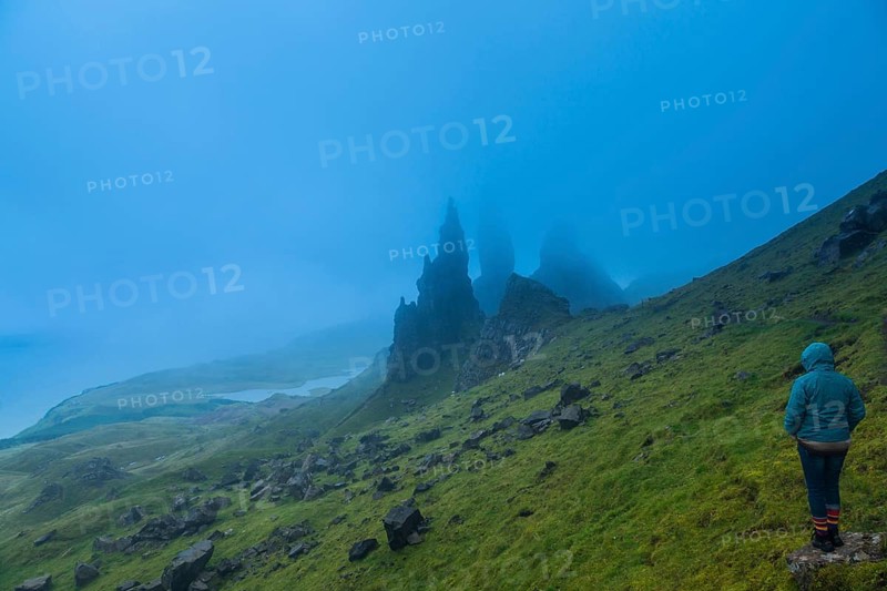 UK. Scotland. Isle of Skye. A tourist looking at the Old Man of Storr during a storm