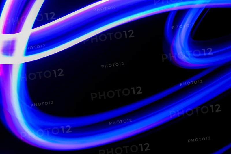 Vibrant blue and purple neon light trails create an abstract design on a dark background, capturing motion with long exposure photography to evoke energy and fluidity