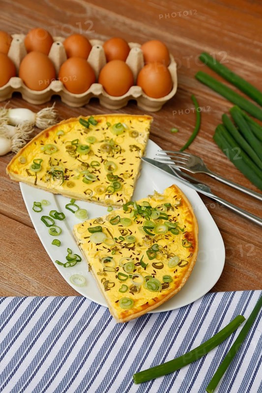 Swabian cuisine, salted cream cake with spring onions, hearty cake on serving platter, salty shortcrust pastry, baked, from the oven, baked goods, spring onions, winter onions, vegetarian, typical Swabian reinterpreted, baking, wooden stirring spoon, cooking spoon, wooden plate, eggs, fresh chicken eggs in egg carton, cutlery, knife, fork, wooden plate, traditional cuisine, food photography, studio, Germany