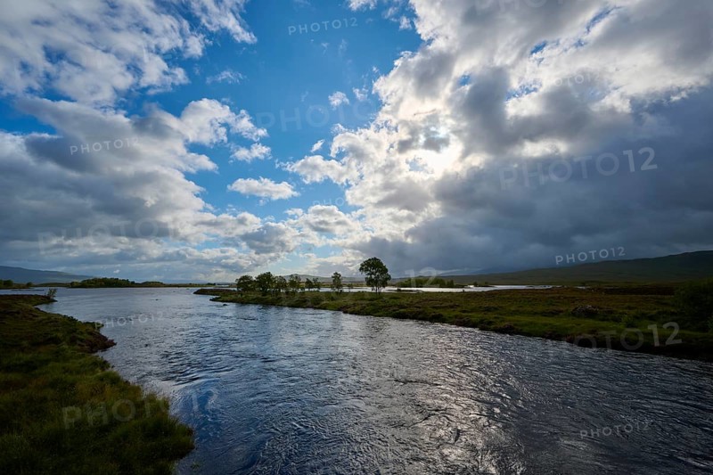 A calm river under a partly cloudy, partly sunny sky in a green landscape, Rannoch Moor, Bridge of Orchy, Scotland, United Kingdom, Great Britain