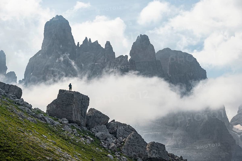 Alpine panorama, mountaineers on a large rock, fog and Torre Di Brentai and Cima Tosa, rocky mountain peaks and mountain landscape, Brenta Mountains, Parco Naturale Brenta-Adamello, Trentino, Italy