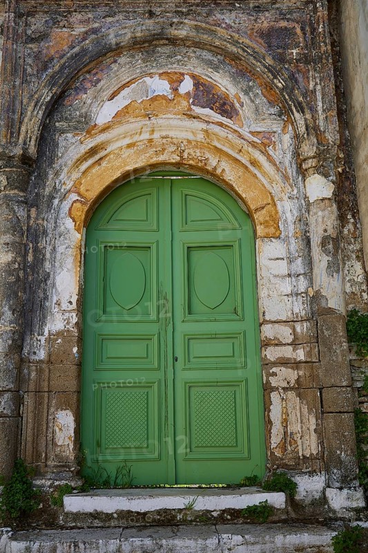 Antique green wooden door in a weathered, arched door frame with rich patina, Symi Town, Symi, Dodecanese, Greek Islands, Greece