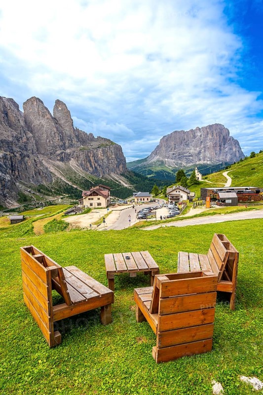 Wooden benches and tables provide a resting spot with breathtaking views of the gardena pass and surrounding dolomites peaks in summer