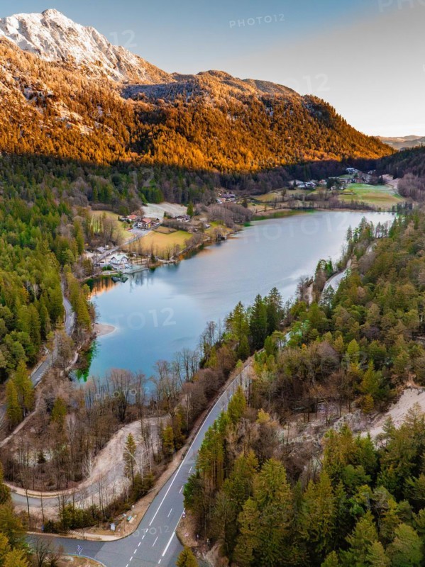 A lake surrounded by an autumn forest and a mountain in the evening light, Thum See, Bad Reichenhall, Bavaria, Germany