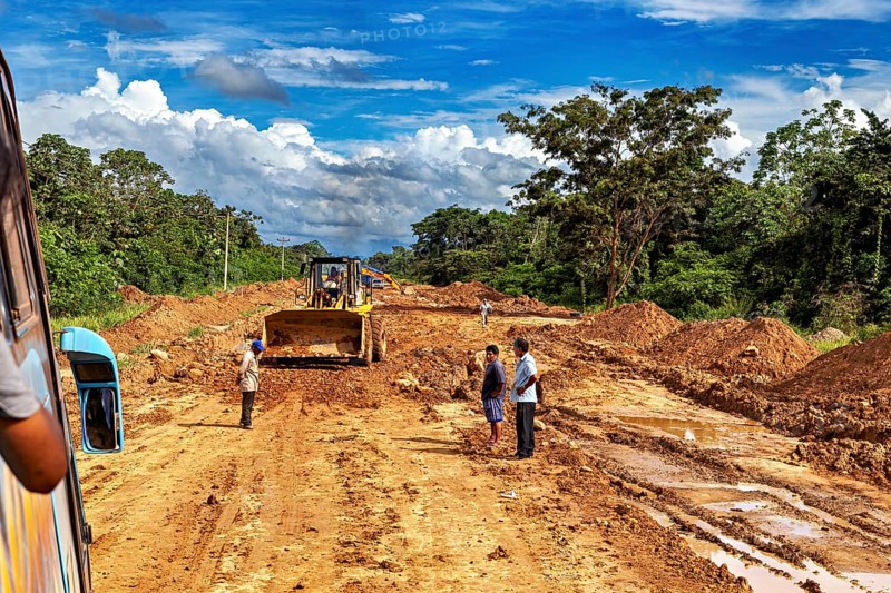 View of a road construction site with people and construction machinery, surrounded by green nature, construction machinery and work on the Yungas Strait in the rainforest of Bolivia