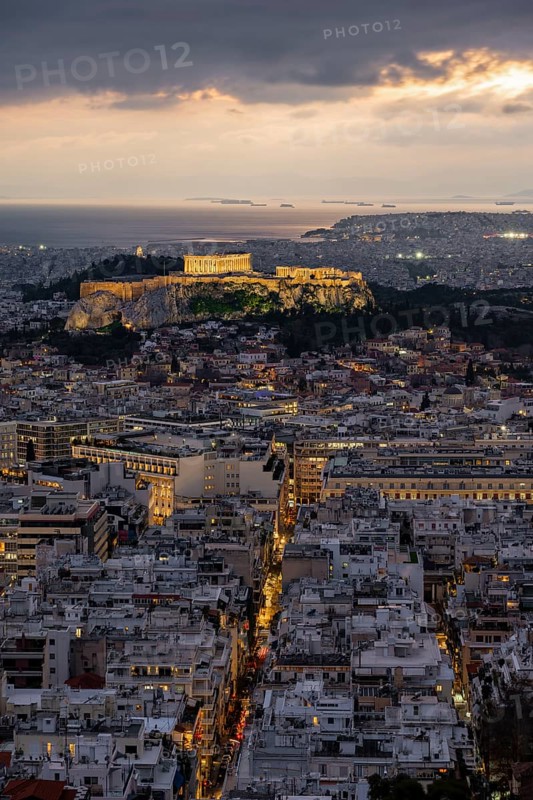 View over the sea of houses of Athens, illuminated Parthenon temple on the Acropolis, from Mount Lycabettus, Athens, Greece
