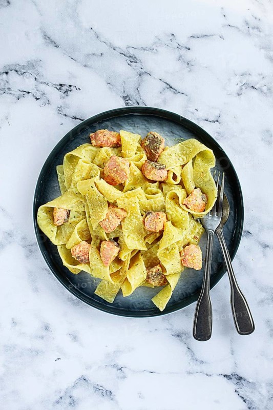 Papardelle pasta, in creamy sauce with salmon, natural light, lifestyle, homemade, on a gray background, no people