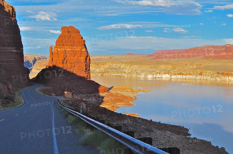 A road leading through a canyon-like landscape with a calm lake, in the light of sunset, Lake Powell, Arizona, USA