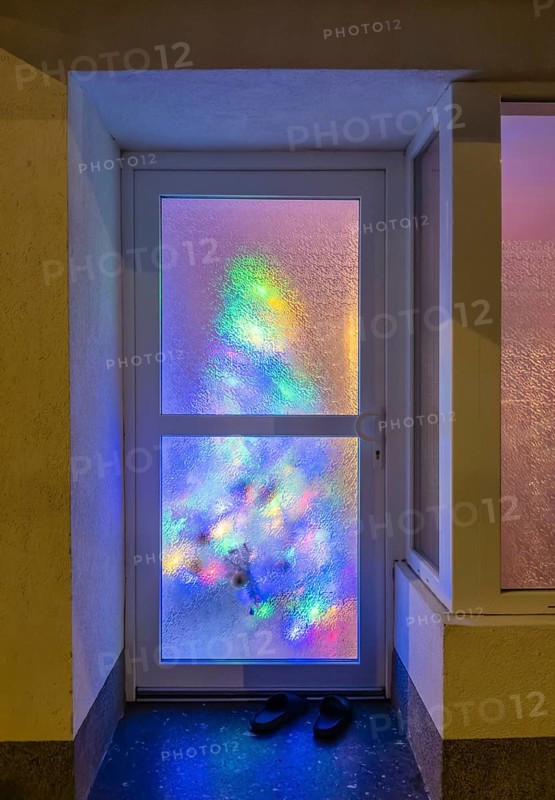 Reflection of a colourfully decorated Christmas tree in a pane of frosted glass in Düsseldorf, Germany