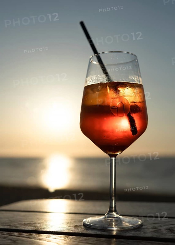 Glass of Aperol Spritz against the light at sunset