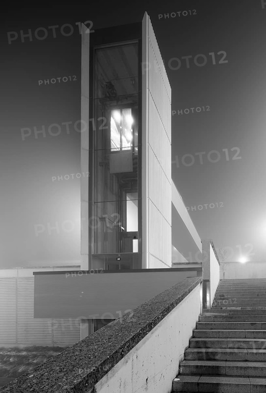 A striking image of a modern urban elevator enveloped in heavy mist, creating a mysterious and atmospheric cityscape scene at night