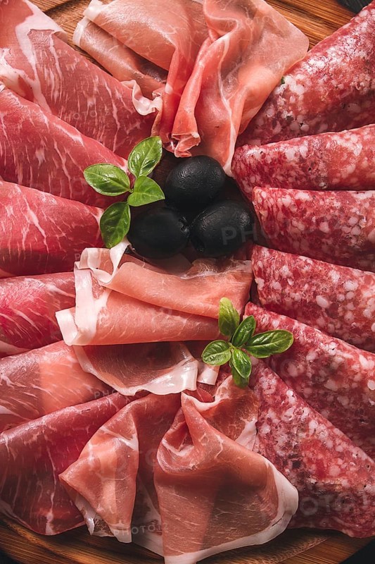 Assortment, sliced meat appetizer, prosciutto, salami and ham, with olives, breakfast, top view, close-up, no people
