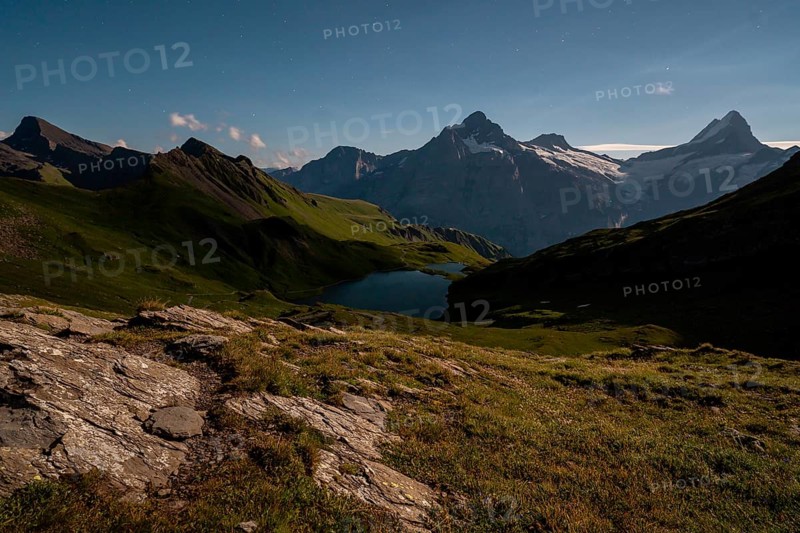 A stunning alpine landscape at Bachalpsee, Switzerland, framed by majestic mountain peaks under a clear sky, with a serene lake reflecting the natural beauty and tranquility