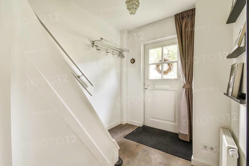 A stylish and welcoming entrance featuring a staircase, a doorway to the outside, and natural light streaming in, creating a bright atmosphere