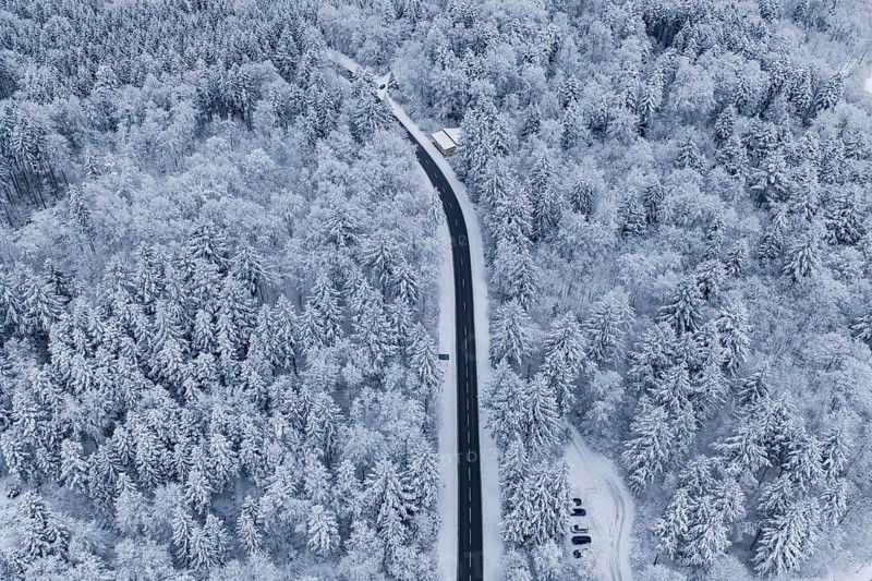 Aerial view of a road in a large, snowy forest, Gechingen, Calw district, Germany