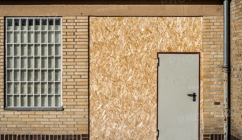 Old building with brick walls and a door covered with OSB panels