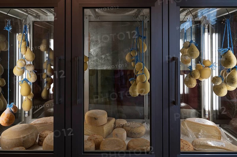 Maturing cheeses in display cases in a specialist shop. Romania