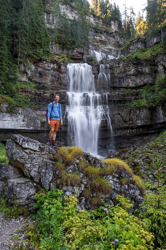 Hiker standing in front of Cascata di Mezzo waterfall, long exposure, Vallesinella, Brenta, Trentino, Italy