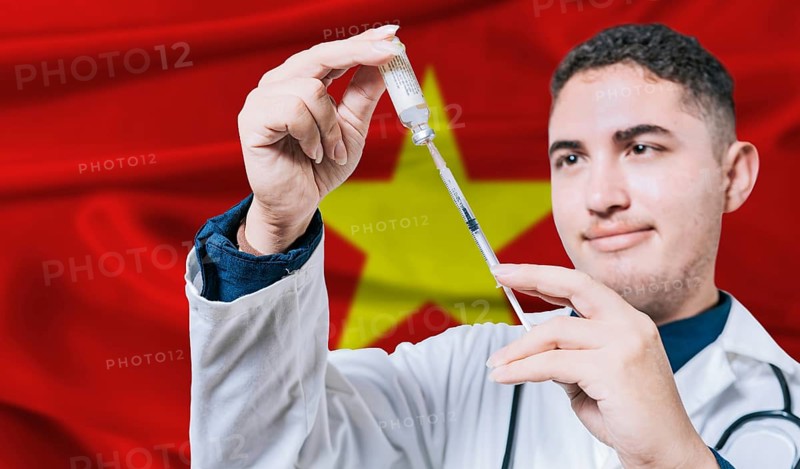 Doctor holding syringe on Vietnam flag background. Medical professional holding syringe with Vietnamese flag in the background
