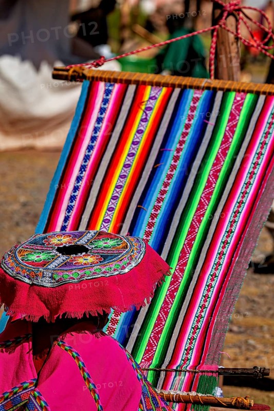 Close-up of a traditional weaving process with colorful fabric, elderly traditionally dressed lady from Peru weaving a shawl