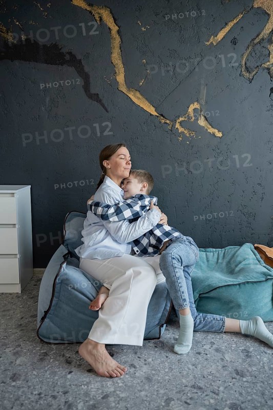 A heartfelt moment captured as a mother lovingly embraces her child, both smiling and comfortable, creating a warm and intimate atmosphere in a cozy home setting