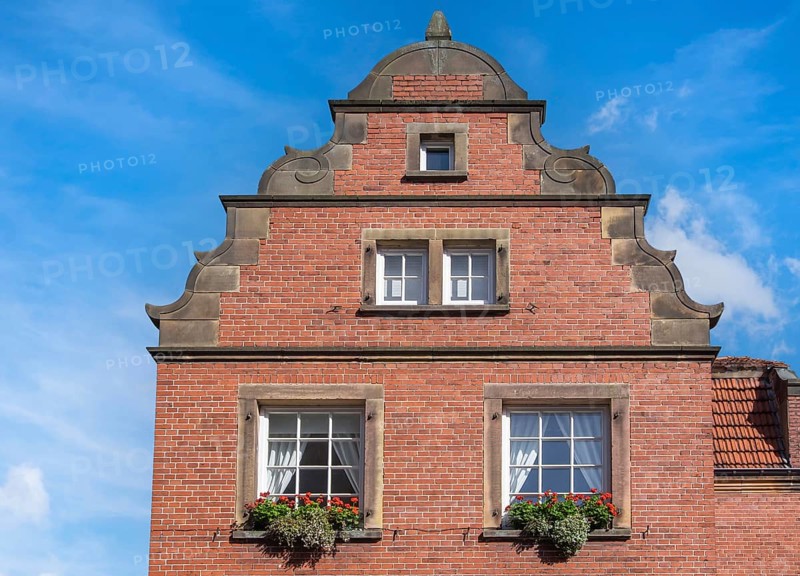 Traditional brick building with windows and flowers against a clear blue sky, Münsterland, North Rhine-Westphalia, Germany