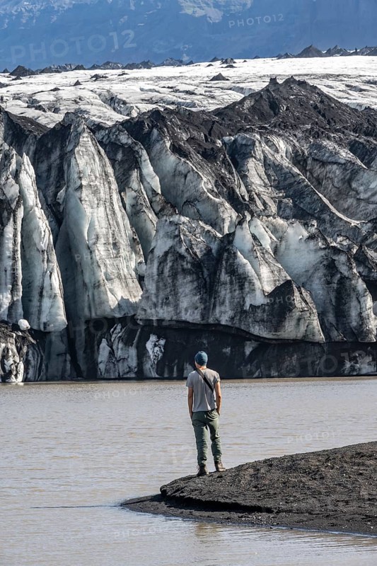 Tourist at the lakeside of a glacier lagoon, glacier tongue with crevasses and lake, Sólheimajökull, South Iceland, Iceland