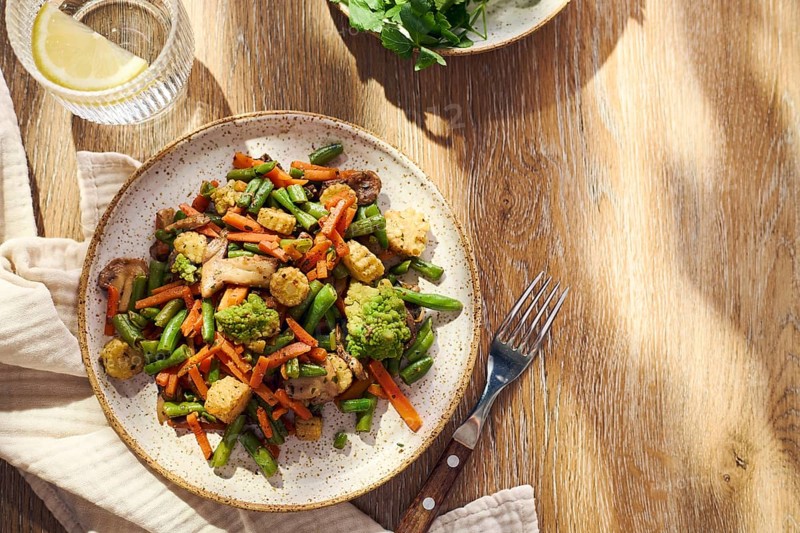 Plate of stir-fried mixed vegetables with green beans, carrots, baby corn, romanesco and mushrooms