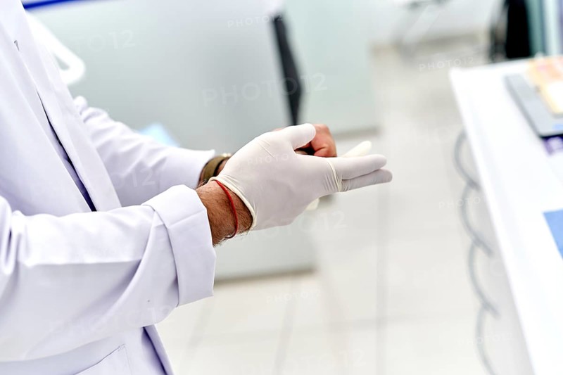 Dentist carefully putting on sterile gloves in a modern dental clinic. White lab coat and professional setting ensure a clean and hygienic environment for patient care